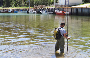 A hydrographer conducting a bathymetric survey of a shallow area in a fishing harbour