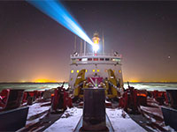 Night photo of the back of a vessel equipped with a powerful projector