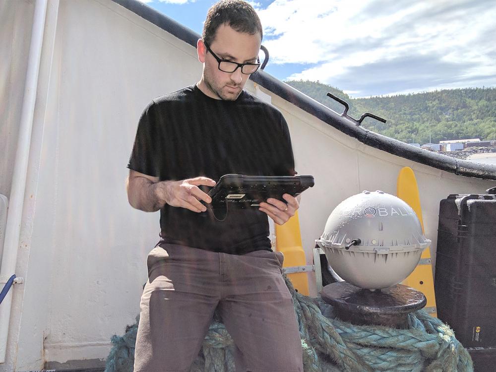 Photo of hydrographer Yann Côté-Nadeau with the HydroBall (40 cm diameter sphere)